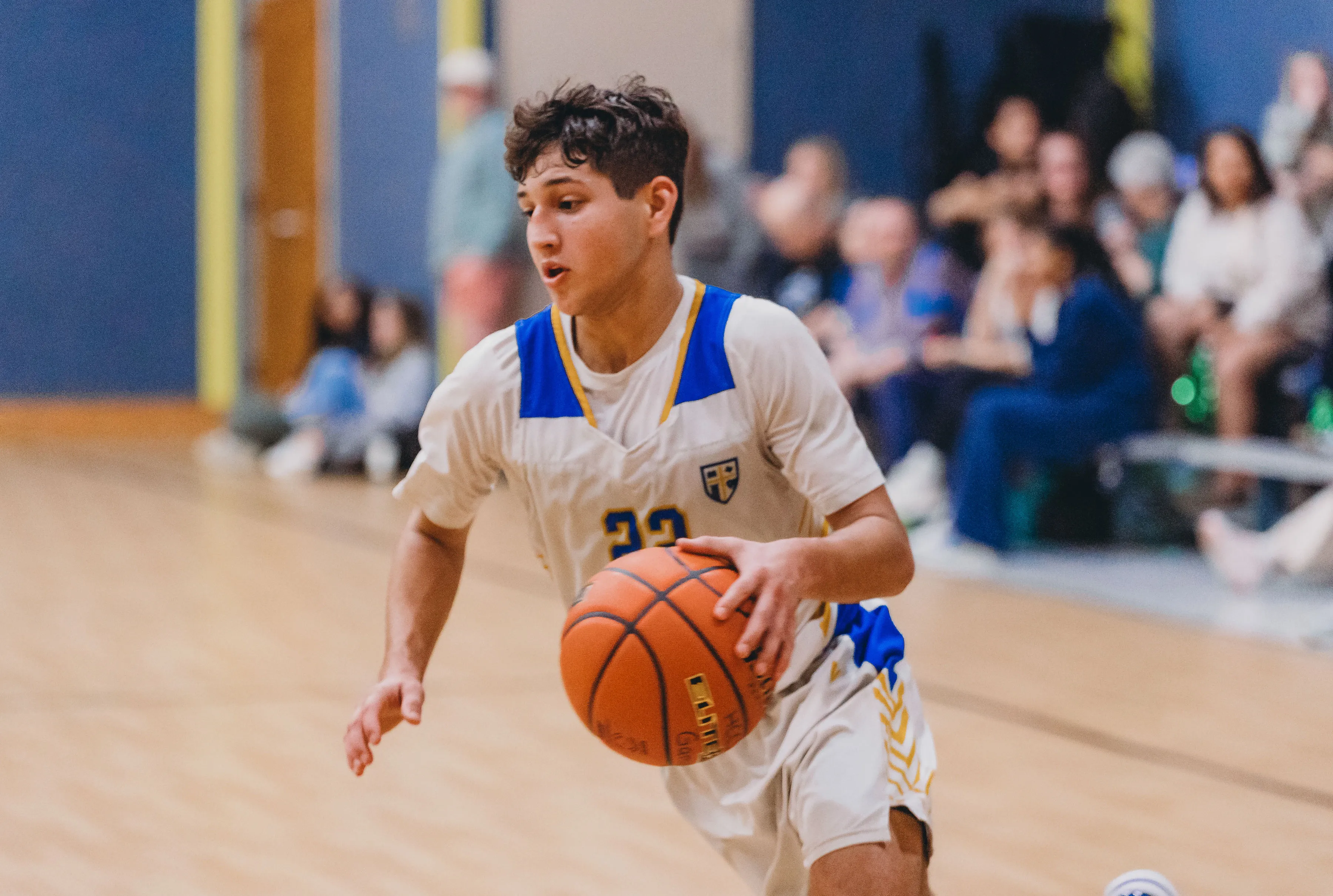 A Rams basketball player driving the ball up the court