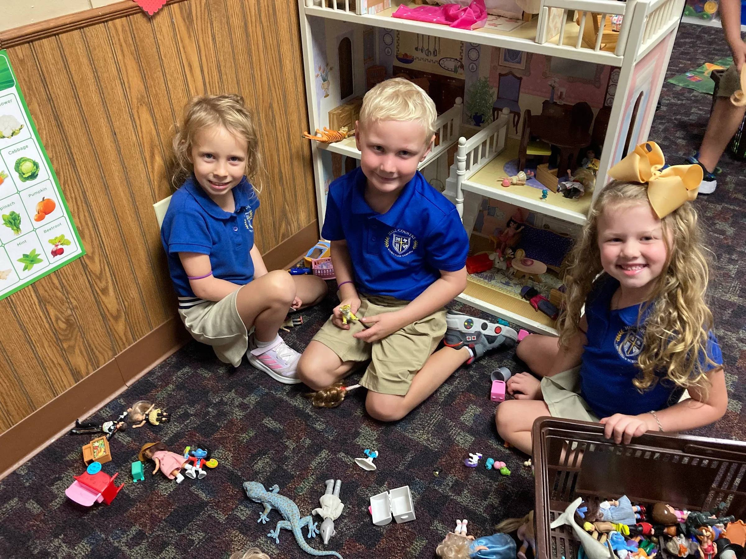 Kindergarten students playing together at the dollhouse in their classroom