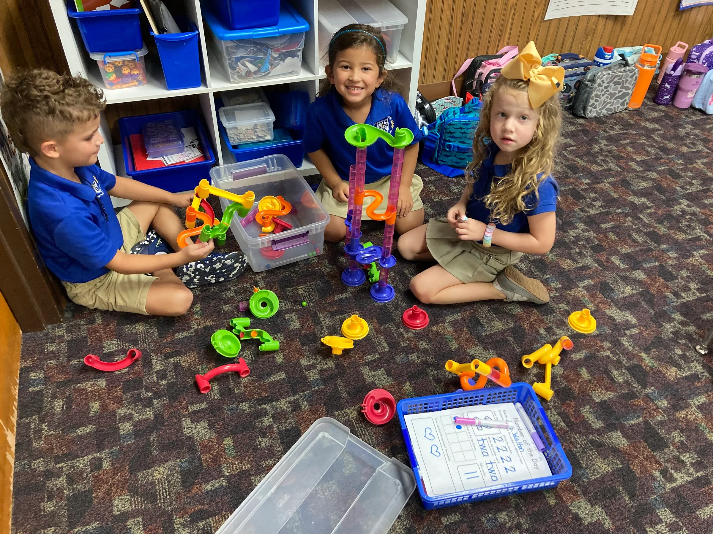 Young HCCS students building with blocks and toys on the classroom floor